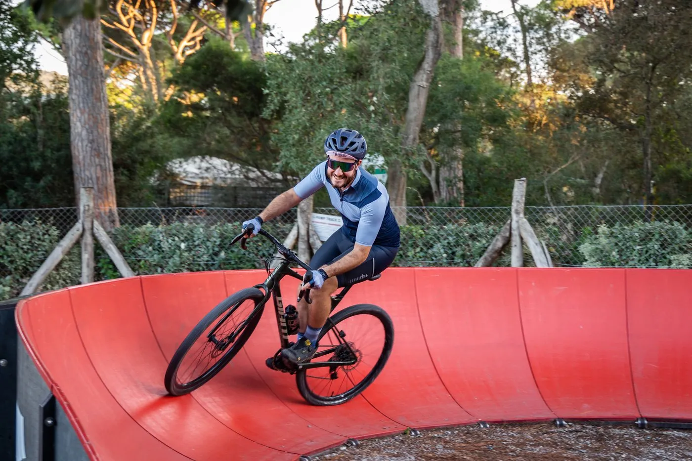 A rider on the red pump track among the pines of PuntAla Camp &amp; Resort